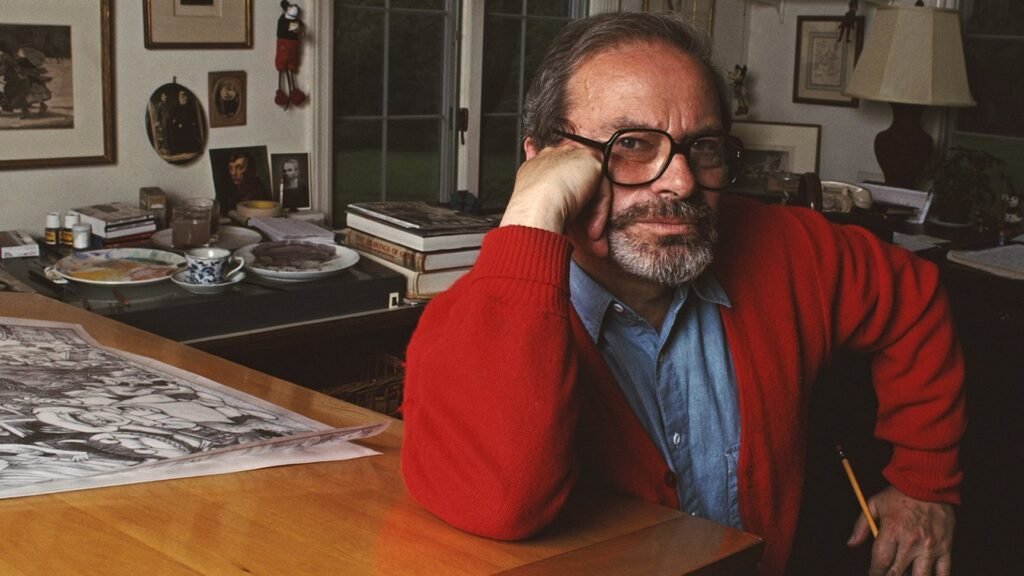 Maurice Sendak sitting at a table.